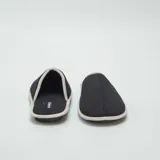 Pantuflas mules negras con borde gris.