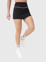 Falda deportiva negra con short incorporado y cintura alta con detalle de línea blanca.