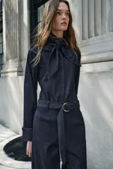 Pantalón de jean azul oscuro, corte wide leg, tiro alto, con cinturón de la misma tela y hebilla metálica.
