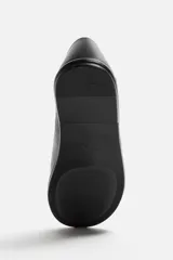 Mocasín negro de piel con construcción desestructurada y suela fina.