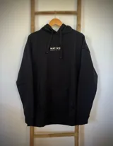 Buzo hoodie negro de corte oversize con capucha y cordón ajustable. Estampado en la espalda con diseño de dos palmeras y el sol dentro de un arco.