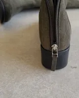 Bota alta de cuero color verde musgo, con caña recta, taco bajo y cierre lateral. Incluye funda de cuero con cierre.