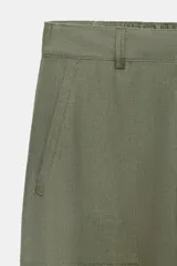 Pantalón capri color verde militar confeccionado en lino, de tiro medio, con bolsillos laterales y traseros. Cierre frontal con cremallera y botón.