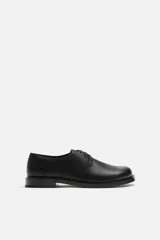 Zapato de vestir de cuero negro, tipo derby con cordones, punta redondeada y suela con ligero tacón.