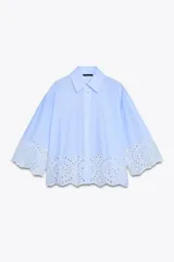 Camisa celeste de popelina con cuello solapa y manga ancha por debajo del codo. Bajo acabado con bordados perforados. Cierre frontal con botones.