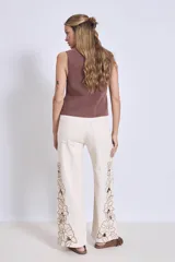Pantalón de jean color crudo con bordados florales y aberturas en las piernas.