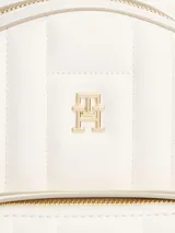 Mochila blanca acolchada con logo de Tommy Hilfiger en dorado. Tiene un asa superior, correas ajustables, cierre de cremallera, bolsillo interior con cremallera y bolsillo exterior con cremallera.