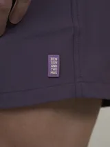 Short de baño verde con estampado de margaritas blancas y cordón ajustable naranja.