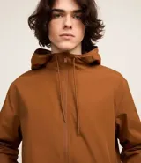 Campera rompevientos color verde oliva, con capucha ajustable con cordón, cierre frontal con cremallera, bolsillos laterales con cremallera y puños elásticos.
