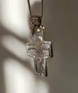 Collar con dije de cruz plateada con la figura de Cristo en relieve.