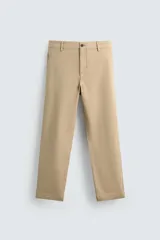 Pantalón chino color beige, de corte recto y tiro medio. Confeccionado en tejido de algodón con elasticidad, con bolsillos laterales y traseros de vivo. Cierre frontal con cremallera y botón.