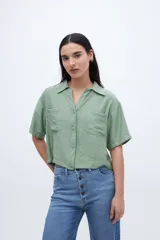 Blusa verde con escote en V, cuello camisero, manga corta y dos bolsillos en el pecho.
