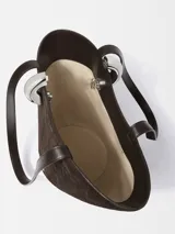 Bolso cubo asimétrico de ante marrón con relieve de cocodrilo, asas para llevar en la mano o al hombro, correa cruzada extraíble, cierre de anilla de metal plateado, bolsillo interior con cremallera, detalles pespunteados, logotipo y herrajes de metal plateado e interior forrado completo de algodón.