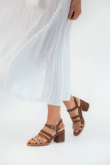 Sandalias de cuero marrón con múltiples tiras y hebilla lateral.