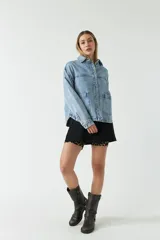 Campera de jean celeste con bolsillos tipo cartera y cierre frontal con botones.