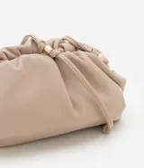 Cartera transversal pequeña color beige, confeccionada en material sintético con bretel fino de cordón con detalles de metal.