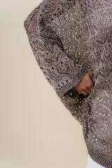 Buzo tejido liviano color bronce/marrón con diseño calado y textura sutilmente brillante. Presenta un calce amplio y mangas amplias, con detalle de tiras entrecruzadas en la espalda.