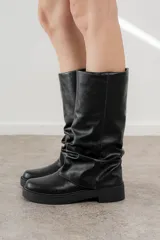 Bota de caña media color negro, confeccionada en cuero sintético con efecto arrugado, suela track y plataforma baja.