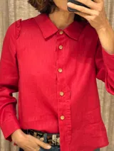 Camisa roja de lino con cuello clásico, cierre frontal con botones de madera y mangas largas con volados en los hombros y en el frente.