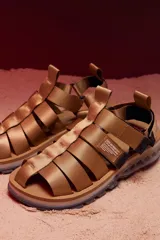 Sandalias con tiras de tela color beige, suela gruesa con detalles geométricos y ajuste con velcro.