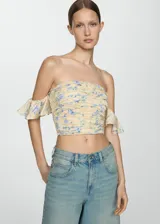 Top strapless color crema con estampado floral en tonos azules, detalle de frunces y mangas cortas con volantes.