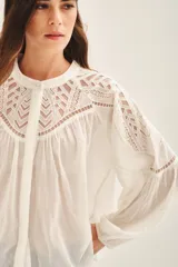 Camisa blanca de algodón con corte amplio, bordado a tono en canesú delantero, trasero y hombros. Mangas largas con volumen y elástico en los puños.