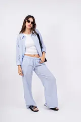 Camisa a rayas verticales color beige y blanco, con cuello clásico, cierre frontal con botones y mangas largas.