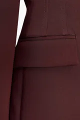 Blazer marrón de corte entallado, con cuello solapa, manga larga, bolsillos delanteros con solapa y cierre frontal con un botón.