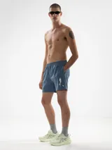 Short de baño azul con bordado de sirena en la pierna izquierda. Tiene calce sastrero, cintura elástica con cordón ajustable, bolsillos laterales y bolsillo trasero con cierre. Incluye suspensor de malla fina hipoalergénico.