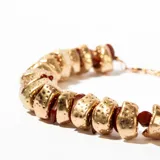 Collar corto con cuentas de piedra color borgoña y piezas de metal dorado con textura irregular.