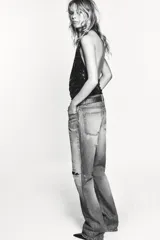 Top halter de tul color gris claro, con escote fluido drapeado y espalda descubierta. Presenta bordados con aplicación de abalorios en tonos oscuros y dorados.