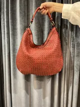 Cartera hobo grande color ladrillo con diseño tejido.