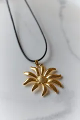 Collar plateado con dije en forma de flor con centro texturizado y tiento negro de 120 cm.