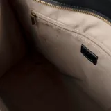Cartera tote grande color negro, confeccionada en cuero sintético. Tiene doble asa de mano trenzada, correa de hombro ajustable y extraíble, cierre superior, bolsillo interno y logo XL dorado en el frente.