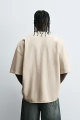 Camiseta color beige de corte holgado, cuello redondo y manga corta.