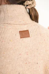 Sweater beige con cuello alto doble, textura acanalada y tajos laterales.