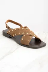Sandalias bajas de cuero color marrón con tiras cruzadas y tachas doradas.