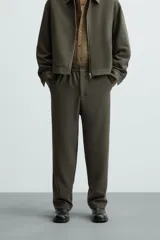 Pantalón verde oscuro de corte recto, con cintura elástica, bolsillos laterales y un bolsillo trasero. Cierre frontal con cremallera y botón.