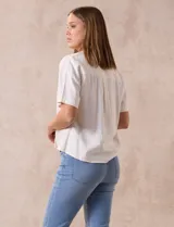 Blusa color blanco de lino, con cuello con solapa y escote en V. Delantera cruzada y mangas cortas. Marca Cable & Gauge.