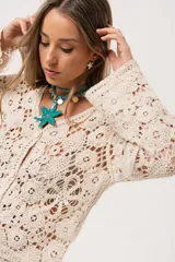 Saco color crudo de crochet con botones y mangas largas.