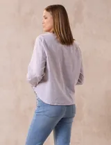 Blusa de algodón a rayas verticales finas en tonos lila y blanco, marca Dash. Escote en V y abertura frontal con botones. Mangas largas regulables con presilla y botón. Terminación de ruedo anudado.
