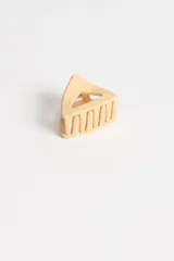 Pinza para el pelo color beige con forma triangular.