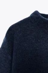 Jersey rojo de punto con cuello redondo y manga larga. Bajo con aberturas laterales.
