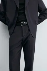 Pantalón de vestir negro de corte relaxed fit confeccionado en tejido con lana. Cuenta con bolsillos frontales y traseros de doble vivo con botón. Cierre frontal con cremallera y botón.