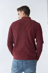 Campera marrón de algodón con cierre frontal, cuello alto, bolsillos laterales, puños y logo bordado en el pecho.