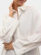 Camisa blanca oversize de manga larga con cuello clásico, puños abotonados y cierre frontal de botones.