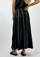 Conjunto de top con breteles finos y pollera larga marrón con líneas verticales blancas.