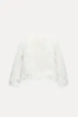 Chaqueta de pelo sintético color blanco, de cuello redondo y manga larga. Tiene bolsillos delanteros, forro interior y cierre frontal con ganchos metálicos forrados.