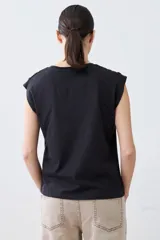 Remera verde pistacho de corte recto, con cuello en V y botones decorativos en los hombros.