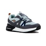 Championes deportivos de hombre, modelo Bariloche, con base de malla textil color celeste pálido y superposiciones en tonos de gris oscuro y azul marino. Presentan una entresuela gruesa blanca y detalles en negro en la suela y talón, donde se lee "MAX PROTECT".